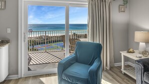 A balcony with a view of the beach and ocean, a blue chair, a small table with a lamp, and a white wall with a plant. - 🌊 Islander #601 -Gulf Views of the Most Beautiful Beaches in the World! 🏖️ (Destin)