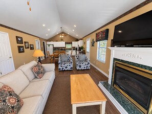 A living room with a sofa, two patterned armchairs, a coffee table, a fireplace, and a kitchen in the background. - Our Tennessee Mountain Home - Great Location!  Close To All The Action! (Pigeon Forge)