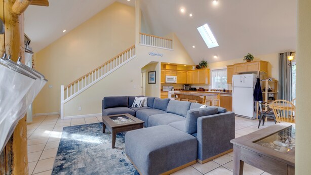 A spacious living room with a sectional sofa, a glass coffee table, and a staircase leading to an upper level. - #119 Sunshine Shores (Pacific City)