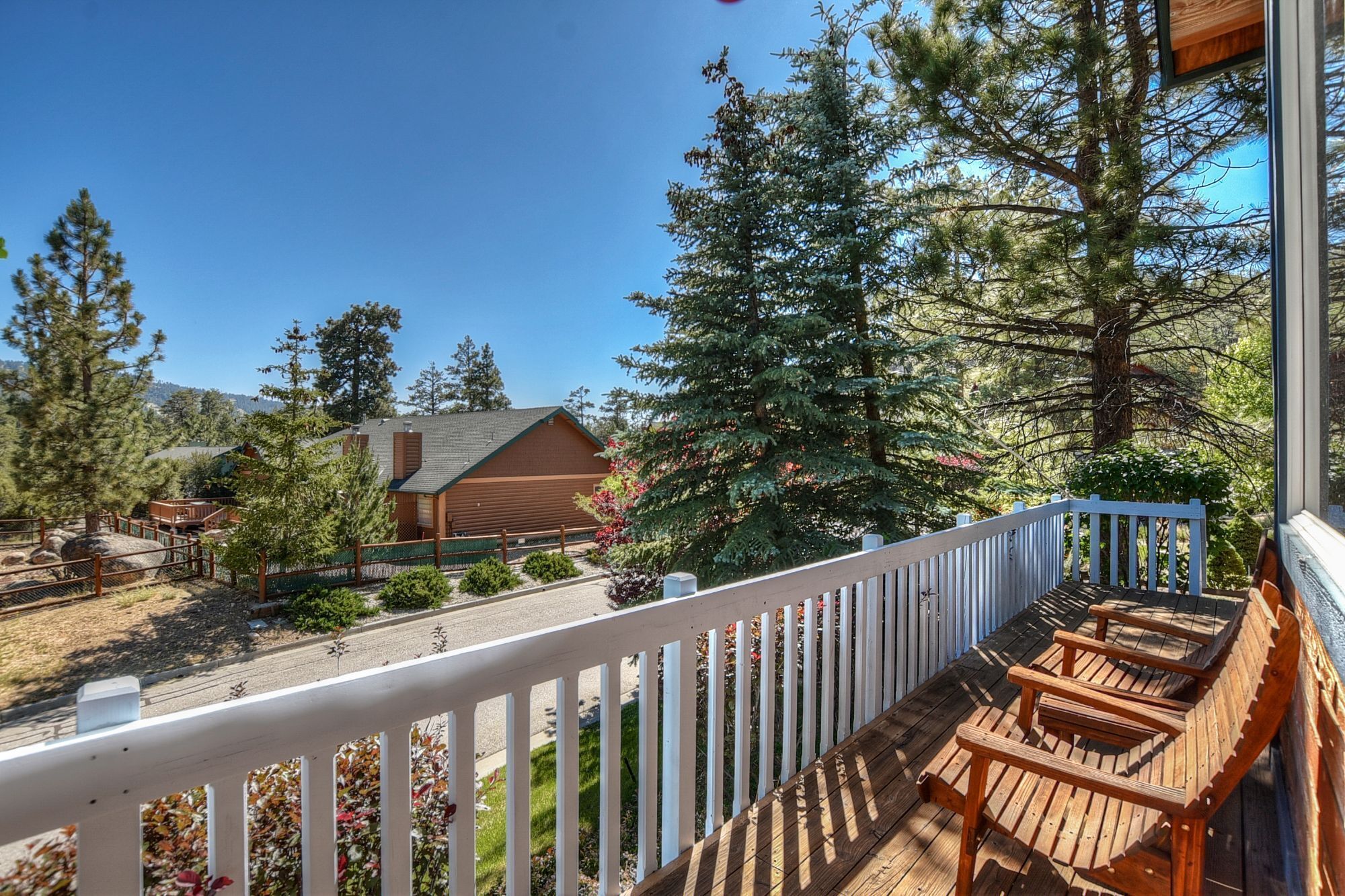 A wooden deck with outdoor seating, a view of a building, and surrounding trees.