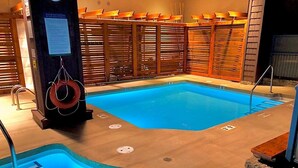 Una piscina con muelle de madera, un puesto de socorrista y un letrero de seguridad.