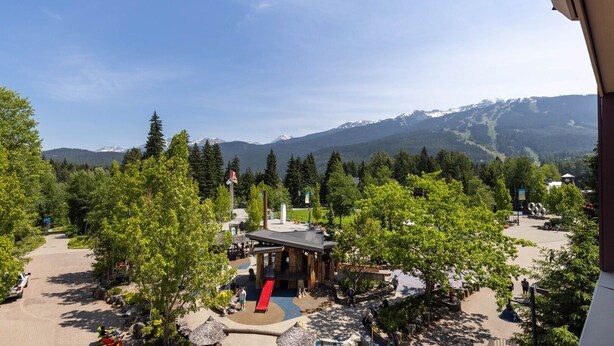 Un resort con vistas a la montaña, asientos al aire libre y un pequeño edificio de techo rojo.
