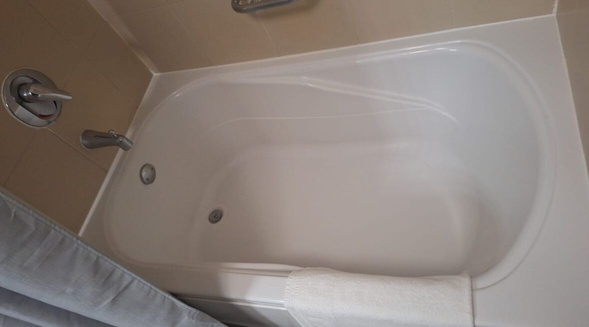 A white bathtub with a faucet and a drain.