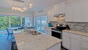Una cocina moderna con armarios blancos, encimera de granito y una isla grande con un fregadero.