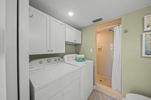 A laundry room with a Whirlpool washer and dryer, a small sink, and a shower area with a curtain.