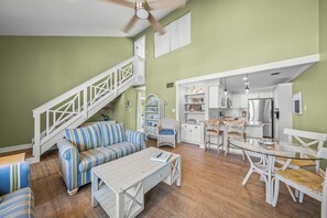 A spacious living area with a staircase, a dining table with chairs, and a kitchen area. - LaPlayita 5 - Anna Maria Island - Condo 2 Bedroom / 2 Bath , maximum occupancy of 4 people. (Holmes Beach)