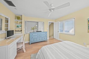 A bedroom with a bed, a dresser, a desk with a computer, a ceiling fan, and a window with blinds. - LaPlayita 5 - Anna Maria Island - Condo 2 Bedroom / 2 Bath , maximum occupancy of 4 people. (Holmes Beach)