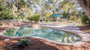 A backyard with a swimming pool, surrounded by trees and a wooden fence. - 13 Sandpiper Street - Pet Friendly (Hilton Head Island)