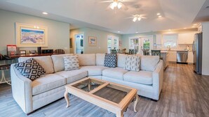 A spacious living room with a sectional sofa, a glass coffee table, and a ceiling fan. - 13 Sandpiper Street - Pet Friendly (Hilton Head Island)