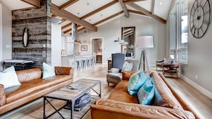 A spacious living area with a high ceiling, exposed wooden beams, a stone accent wall, and a large clock on the wall. - Sunrise Ski Haus: Peak 8 Breckenridge Home with Hot Tub and Views, Near Slopes (Breckenridge)