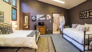 A bedroom with two beds, a dresser, a TV, and artwork on the walls.