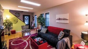 A modern living room with a red sofa, a coffee table, and a staircase leading to another level.