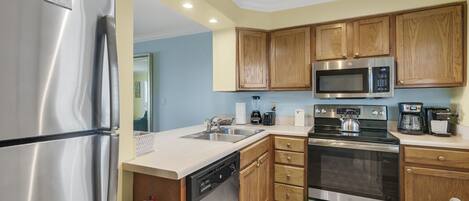 A modern kitchen with stainless steel appliances, wooden cabinets, and a dishwasher.