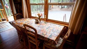 A dining table with a colorful tablecloth, surrounded by wooden chairs. - Montgomery's Cozy Forest Retreat (Greer)