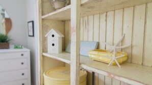 A rustic wooden shelf with a yellow container, a white birdhouse, and a starfish decoration. - Screened Inn c1925! Quiet North End Duplex! Screened porch. Beach Access! (Tybee Island)