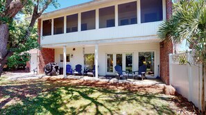 A two-story building with a covered porch, multiple windows, and outdoor seating. - Sea La Vie 4 bedrooms, 3.5 bathrooms (Jekyll Island)