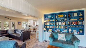 A living room with a blue bookshelf, a leather sofa, and a teal armchair.