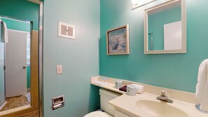 A bathroom with a toilet, sink, mirror, and a framed picture on the wall. - Sea La Vie 4 bedrooms, 3.5 bathrooms (Jekyll Island)