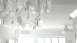 A bright, spacious room with a large window, a ceiling light fixture, and a wooden floor.