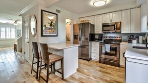 A modern kitchen with white cabinetry, stainless steel appliances, and a wooden island with bar stools.