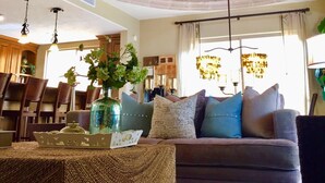 Ein Wohnzimmer mit Ziegeldecke, einem Kronleuchter, einer Couch mit Kissen und einem Tisch mit einer Vase.