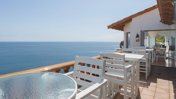Una terraza con mobiliario blanco con vistas al mar.