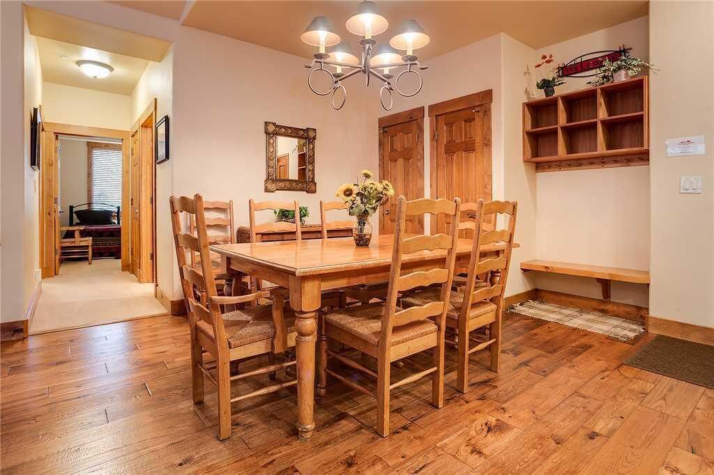 A dining area with a wooden table and chairs, a chandelier, and a mirror on the wall.