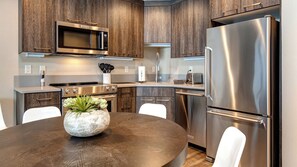 Step into your fully equipped kitchen with sleek stainless steel appliances, warm wood cabinetry, and plenty of counter space for preparing meals. Gather around the cozy dining table to enjoy your morning coffee or plan the day's adventures.