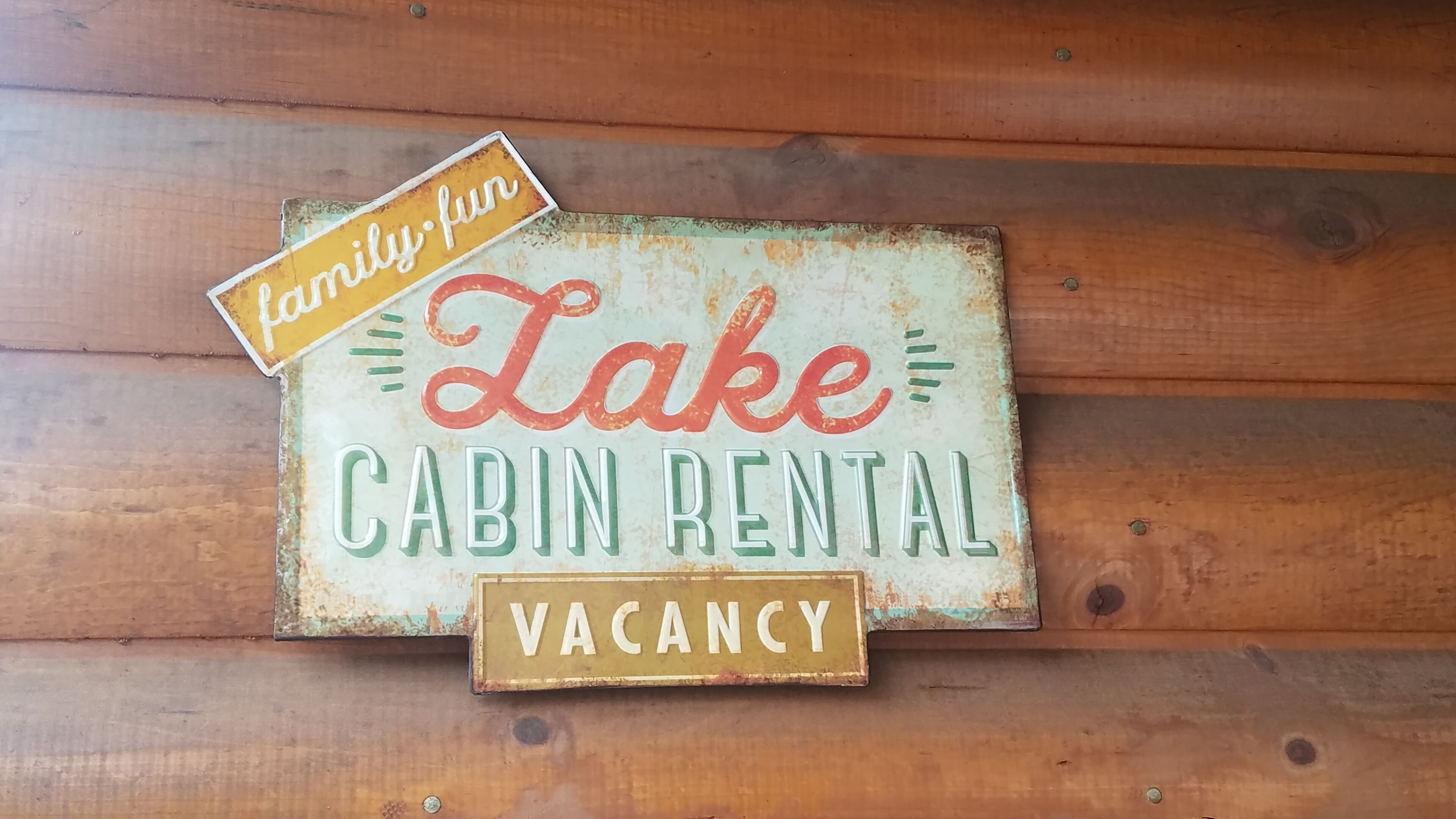 A rustic cabin rental sign with a 'vacancy' label.