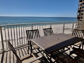 Ein Balkon mit Tisch und Stühlen mit Blick auf einen Strand.