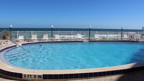 A pool with a 3 FT 3 IN depth, surrounded by white lounge chairs and a white fence. - Oceanfront corner Condo Stunning Views -heated pool Satellite Beach -Cocoa Beach (Satellite Beach)