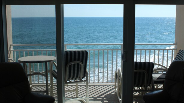 A balcony with a view of the ocean, featuring two chairs and a small table. - Oceanfront corner Condo Stunning Views -heated pool Satellite Beach -Cocoa Beach (Satellite Beach)