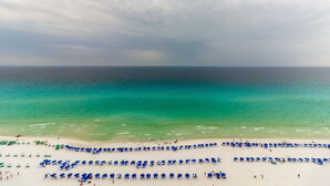 Une plage bordée de rangées de parasols bleus et de sable blanc.