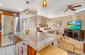 Quarto de hotel com cozinha compacta, cama com vista, televisão e ventoinha.