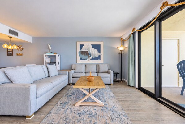 A modern living room with a grey sofa, a wooden coffee table, and a framed artwork on the wall.