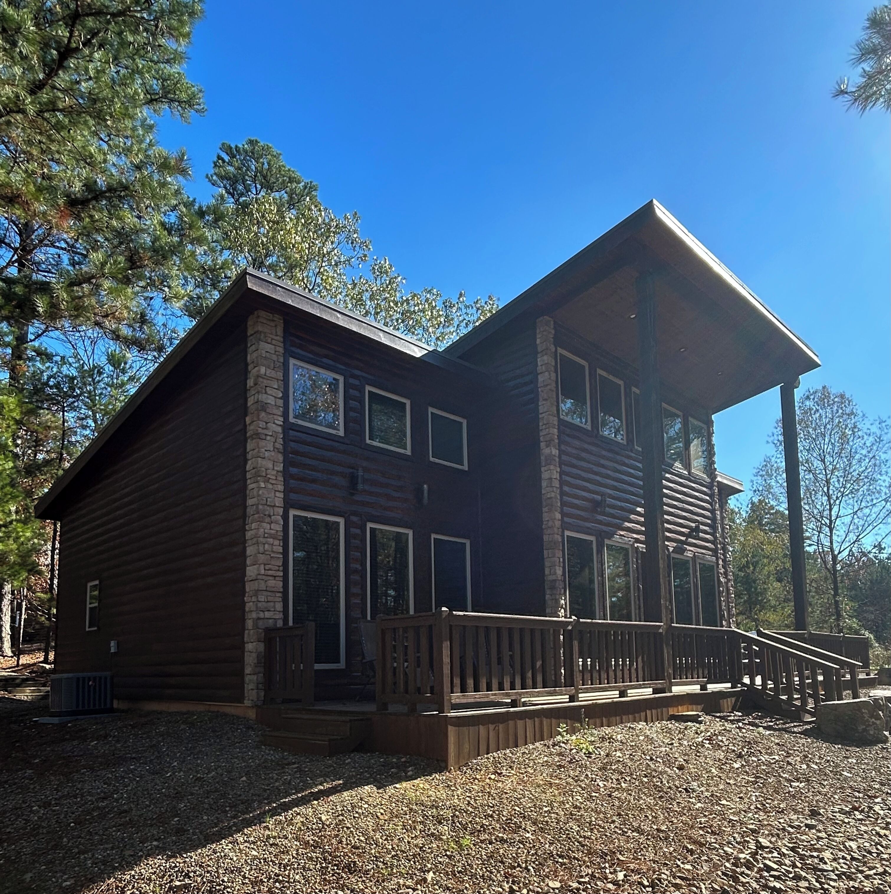 A two-story log cabin with a wooden deck and large windows.