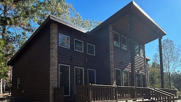 A two-story log cabin with a wooden deck and large windows.