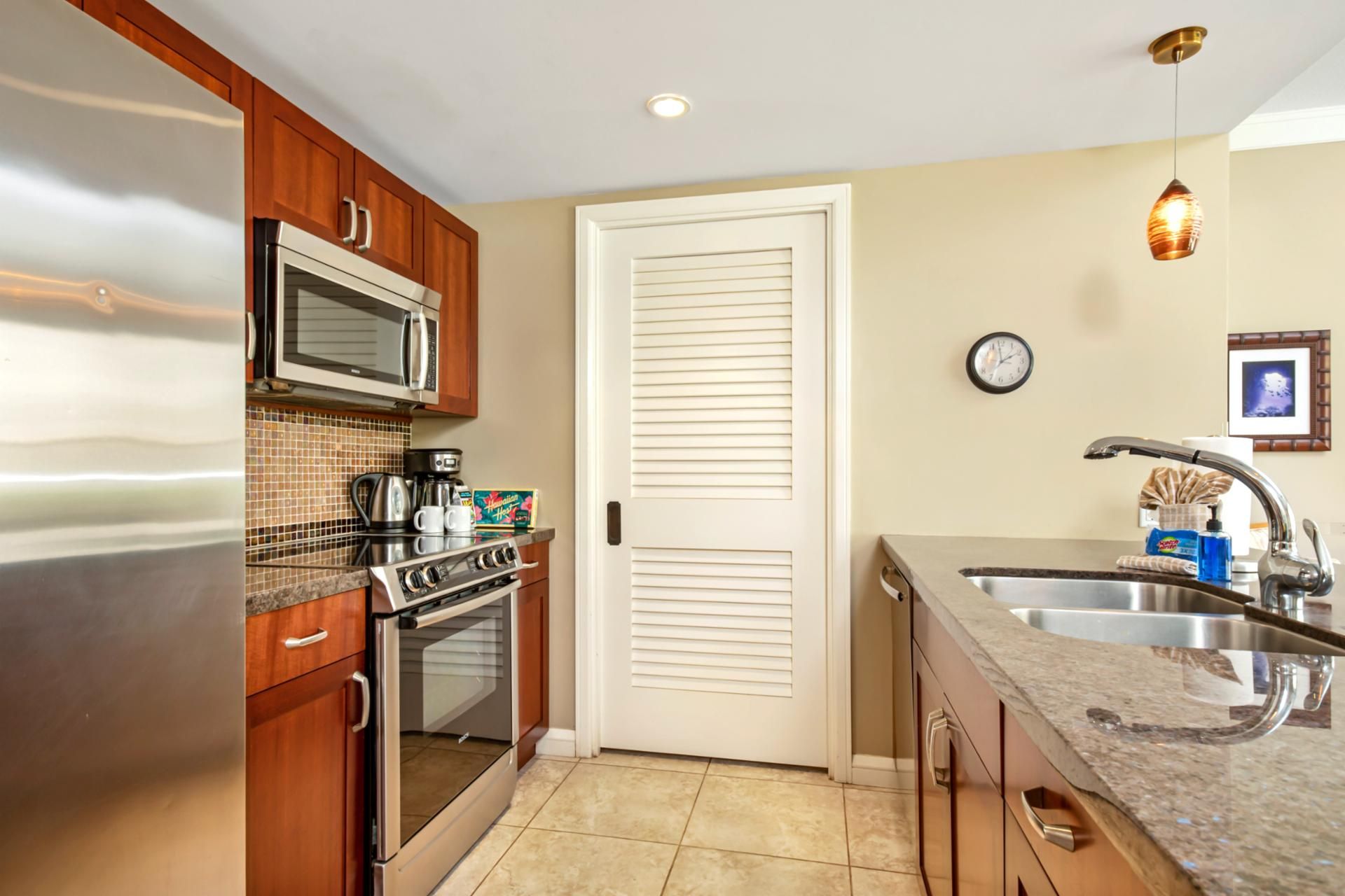 A compact kitchen with stainless steel appliances, a microwave, a coffee maker, and a toaster.