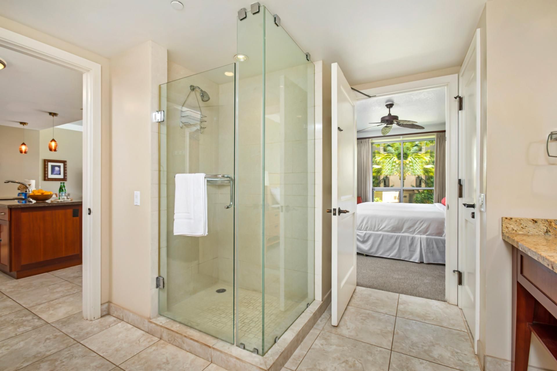 Un baño moderno con ducha envuelta en vidrio, un perchero a la vista y una cama en la habitación contigua.