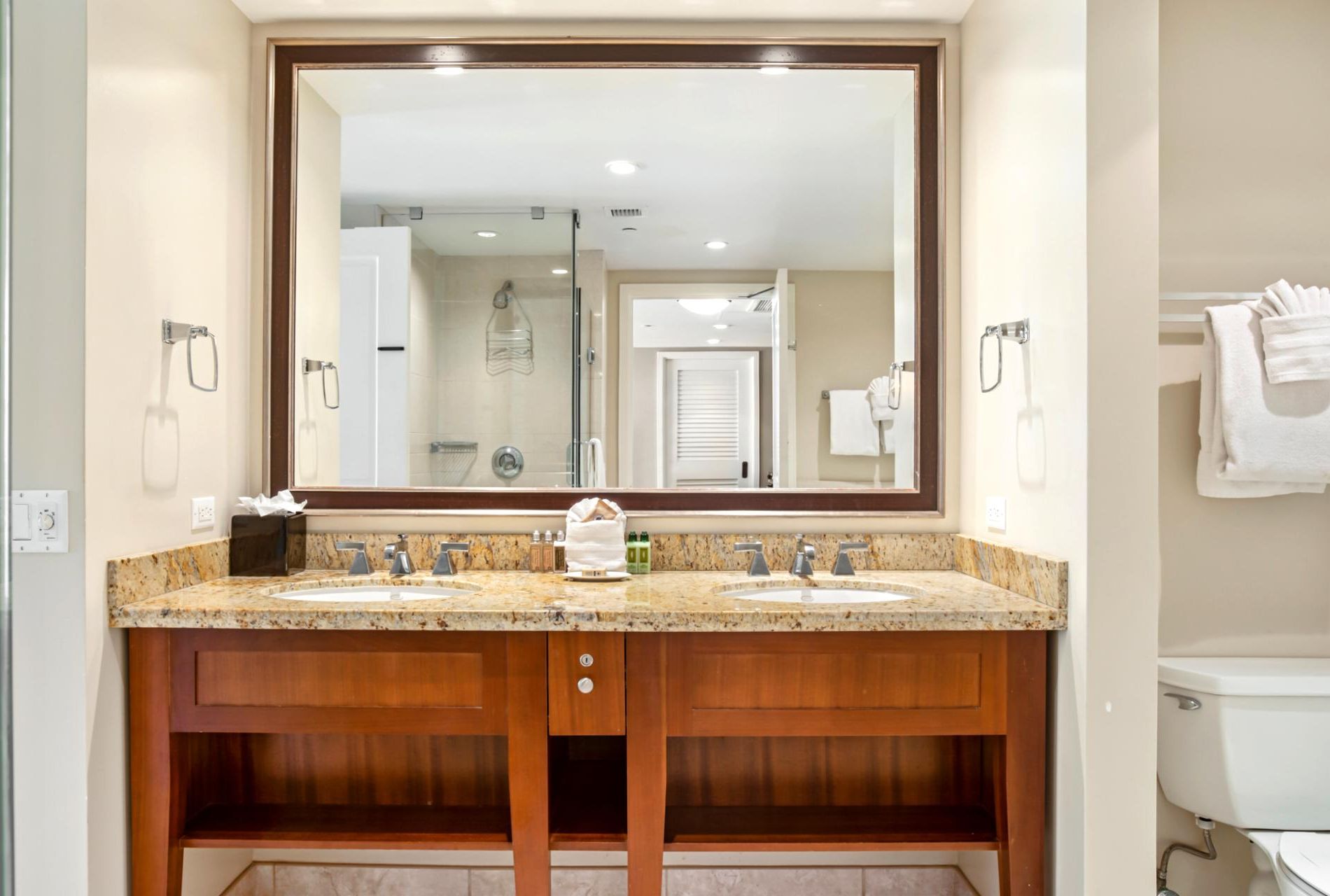 A bathroom with a double sink vanity, a large mirror, and a toilet.
