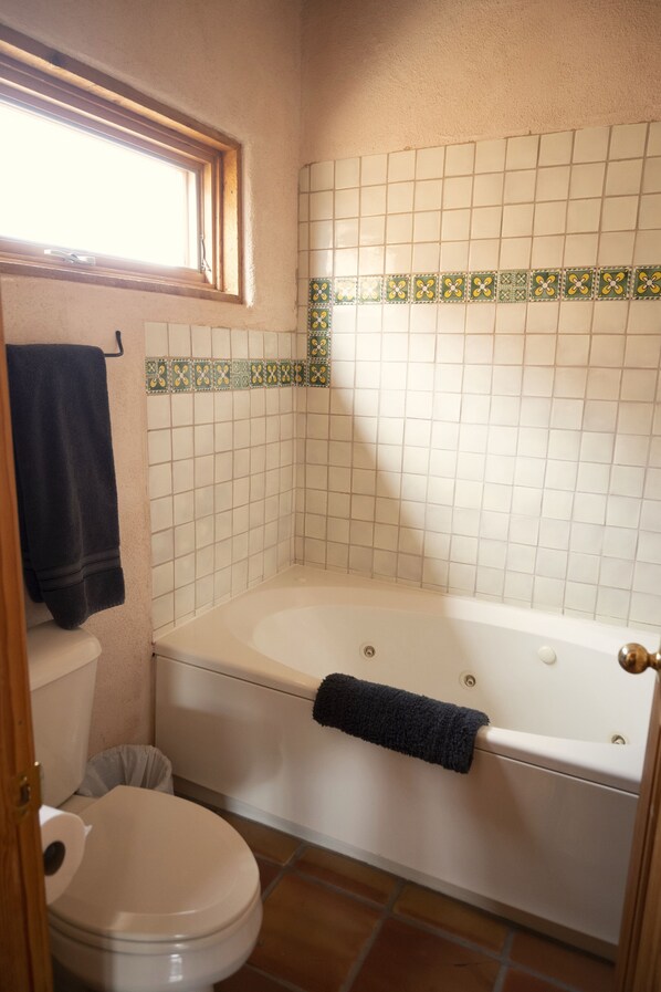 A bathroom with a bathtub, toilet, and a window.