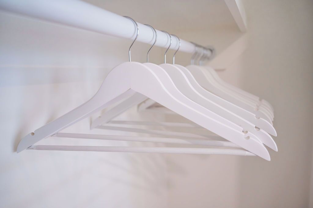 Een witte kledingroede met verschillende witte kleerhangers.
