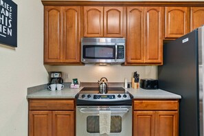 A kitchen with wooden cabinets, a stainless steel microwave, a gas stove, and a refrigerator. - Resort Condo 3BR w Balcony, Free Parking near OCCC (Orlando)