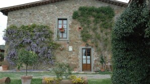 A stone building with a small garden in front, including a tree and potted plants.
