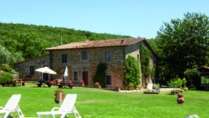 A stone building with a tiled roof, a swimming pool, and outdoor seating.