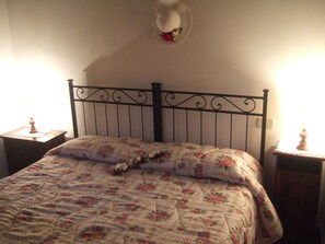 Una cama con colcha floral, un tapiz decorativo y dos lámparas de noche.