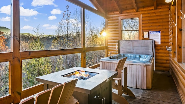 A wooden cabin with a hot tub, a fire pit, and a table with chairs. - Love Me Tender: Amazing Views, Romantic, Fire Pit (Gatlinburg)