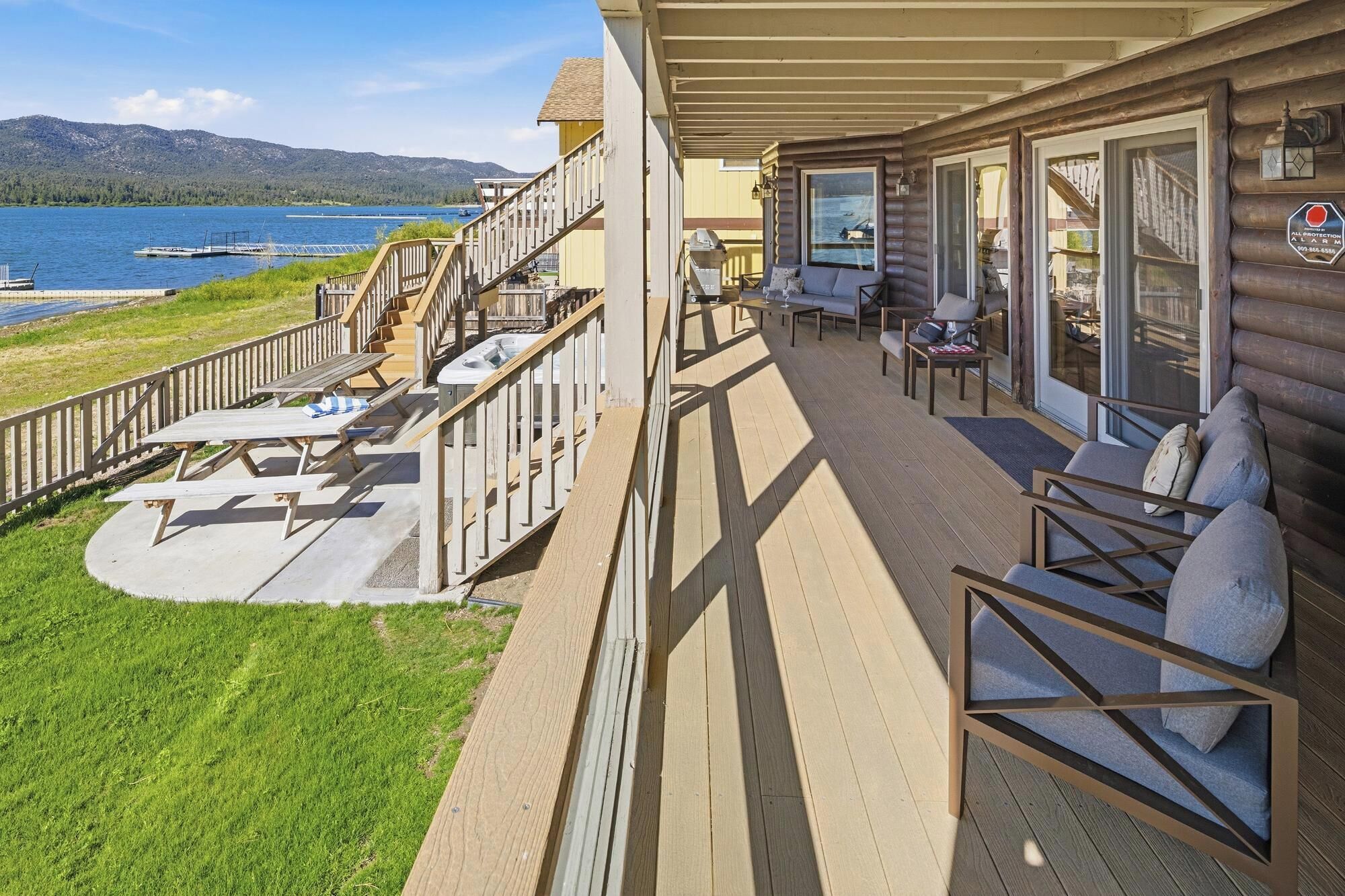 A wooden deck with outdoor seating, a view of a lake, and a mountain in the background.