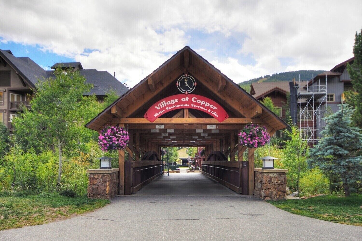 The entrance to Village at Copper with a covered walkway, stone walls, and hanging flower baskets.