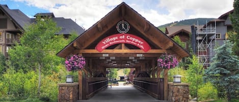 The entrance to Village at Copper with a covered walkway, stone walls, and hanging flower baskets.